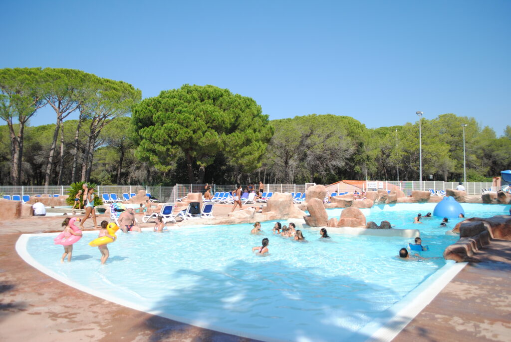 Oasis Village's counter-current swimming pool, with a submerged beach and rocky decor under the pine trees